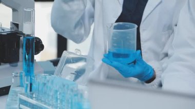 Laboratuvar çalışanı elinde sıvı numunesiyle test tüpü tutuyor.