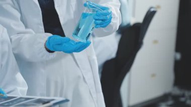 Yakın plan. Eldivenli bilim adamının test tüpü tutuşu.