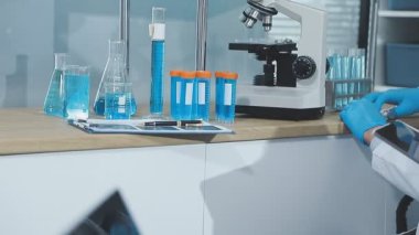 Laboratuvarda mikroskopla çalışan koruyucu maskeli bilim adamı