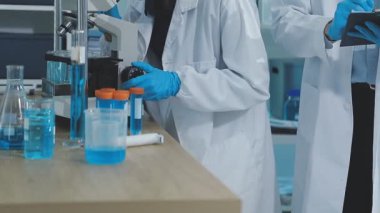 Koruyucu gözlüklü ve ceketli bilim adamı kimya laboratuvarında kimyasal deney üzerinde çalışıyor.