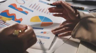 İş adamları mali istatistikleri tartışıyor ve grafikler üzerindeki verileri analiz ediyorlar