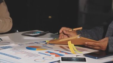 İşadamı laptoptaki verileri analiz ediyor ve ofisinde grafikler var.