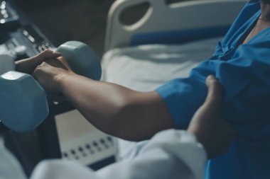 Fizyoterapist, halter egzersizinde bir kadına yardım ediyor.