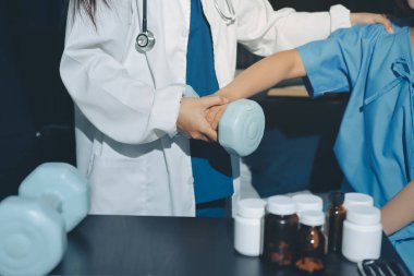 Fizyoterapist, halter egzersizinde bir kadına yardım ediyor.