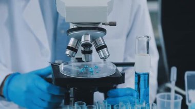 Deney tüpleriyle mikroskop tutan bilim adamı.