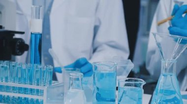 Mavi üniformalı bilim adamı sıvıyla deney yapıyor.