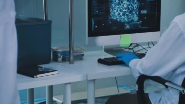 Laboratuvarda bilgisayar üzerinde çalışan laboratuvar önlüklü bilim adamı.