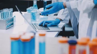 Laboratuvar önlüklü bilim adamı laboratuarda test tüpü tutuyor.