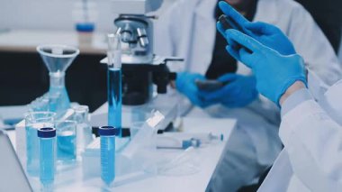 Laboratuvar asistanı elinde sıvı olan bir test tüpü tutuyor.