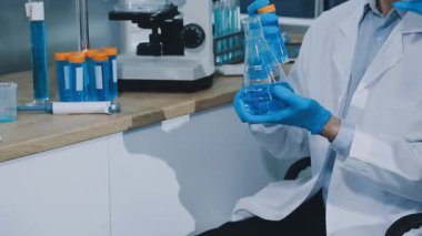 Laboratuvarda mikroskopla çalışan koruyucu eldivenler giyen bilim adamı.