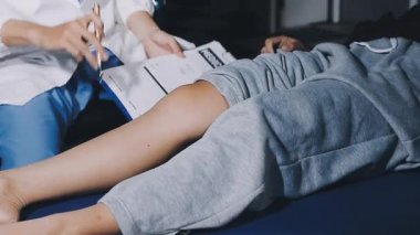 Klinikteki kadın. Doktor hastanın bacağını kontrol ediyor..