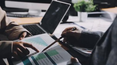 İşletme ekibi, dizüstü bilgisayar ve finansal tabloyla ofiste toplanıyor.