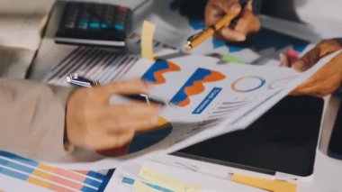 Resmi giysiler içinde genç bir iş kadını elinde kalemle ofiste kağıda notlar yazıyor.