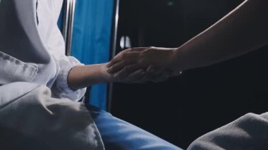 Yakın plan. Hastanede genç bir hastanın elini tutan erkek doktor..