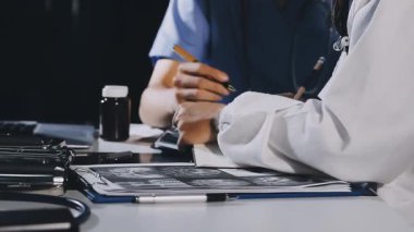 Doktor elinde kalemle pano tutuyor.