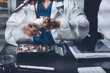 Two doctors and a female nurse meet at a table in the hospital, collaborating on medical tasks using laptops and computers
