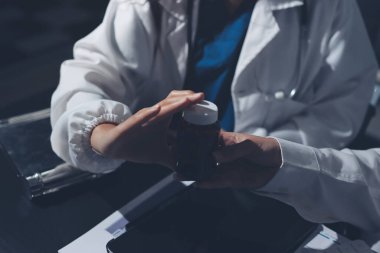 Two doctors and a female nurse meet at a table in the hospital, collaborating on medical tasks using laptops and computers