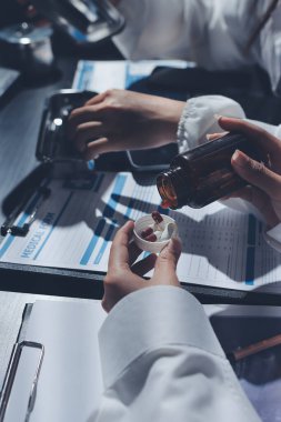 Two doctors and a female nurse meet at a table in the hospital, collaborating on medical tasks using laptops and computers