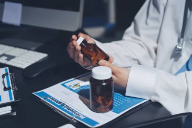 Two doctors and a female nurse meet at a table in the hospital, collaborating on medical tasks using laptops and computers