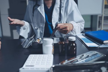 Elinde ilaç şişesi olan kadın doktor hastanın yan etkileri için ilaç kalitesini kontrol ediyor ve hasta bilgilerini hastanede kaydediyor. tıbbi ve sağlık hizmetleri kavramı