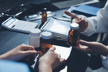 Elinde ilaç şişesi olan kadın doktor hastanın yan etkileri için ilaç kalitesini kontrol ediyor ve hasta bilgilerini hastanede kaydediyor. tıbbi ve sağlık hizmetleri kavramı