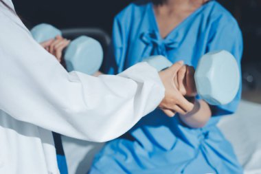 Fizyoterapist, halter egzersizinde bir kadına yardım ediyor.