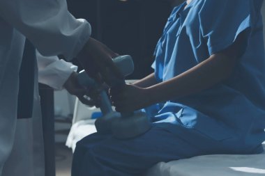 Fizyoterapist, halter egzersizinde bir kadına yardım ediyor.