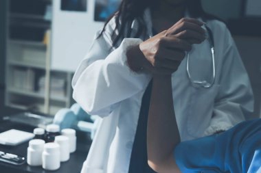 Hastane odasında hastanın dirseğini muayene eden doktor.