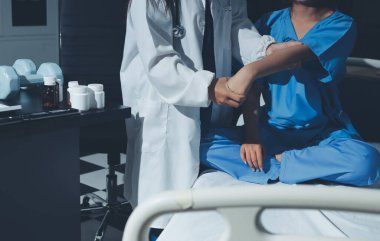 Hastane odasında hastanın dirseğini muayene eden doktor.