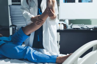 Hastane odasında yaralı bir kadının ayak bileğini inceleyen ve destekleyen doktor, burkulma ya da kırık için tıbbi yardım ve tedavi sunuyor.