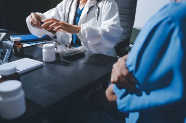 Elinde ilaç şişesi olan kadın doktor hastanın yan etkileri için ilaç kalitesini kontrol ediyor ve hasta bilgilerini hastanede kaydediyor. tıbbi ve sağlık hizmetleri kavramı