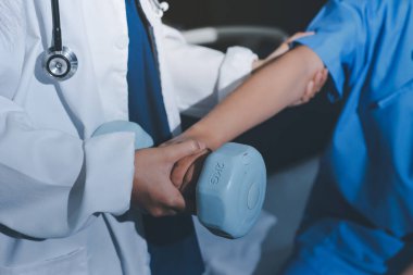 Fizyoterapist, halter egzersizinde bir kadına yardım ediyor.