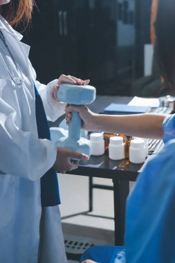 Fizyoterapist, halter egzersizinde bir kadına yardım ediyor.