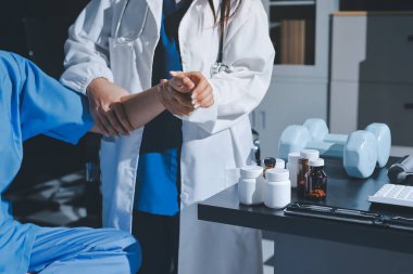 Fizyoterapist, halter egzersizinde bir kadına yardım ediyor.