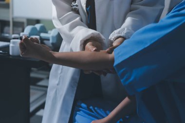 Hastane odasında hastanın dirseğini muayene eden doktor.