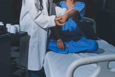 Hastane odasında hastanın dirseğini muayene eden doktor.