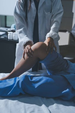 Hastane odasında yaralı bir kadının ayak bileğini inceleyen ve destekleyen doktor, burkulma ya da kırık için tıbbi yardım ve tedavi sunuyor.