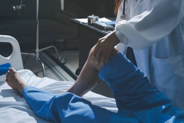 Hastane odasında yaralı bir kadının ayak bileğini inceleyen ve destekleyen doktor, burkulma ya da kırık için tıbbi yardım ve tedavi sunuyor.