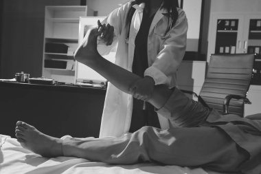 Hastane odasında yaralı bir kadının ayak bileğini inceleyen ve destekleyen doktor, burkulma ya da kırık için tıbbi yardım ve tedavi sunuyor.