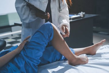 Hastane odasında yaralı bir kadının ayak bileğini inceleyen ve destekleyen doktor, burkulma ya da kırık için tıbbi yardım ve tedavi sunuyor.