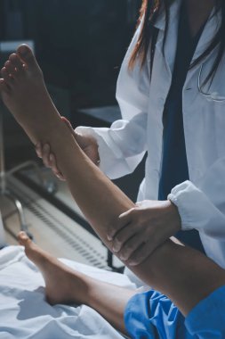 Hastane odasında yaralı bir kadının ayak bileğini inceleyen ve destekleyen doktor, burkulma ya da kırık için tıbbi yardım ve tedavi sunuyor.