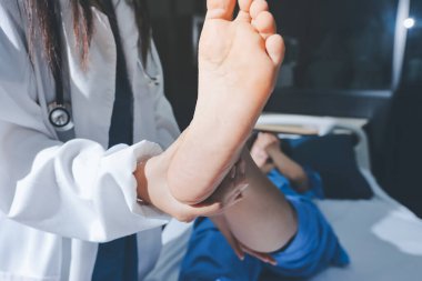 Hastane odasında yaralı bir kadının ayak bileğini inceleyen ve destekleyen doktor, burkulma ya da kırık için tıbbi yardım ve tedavi sunuyor.