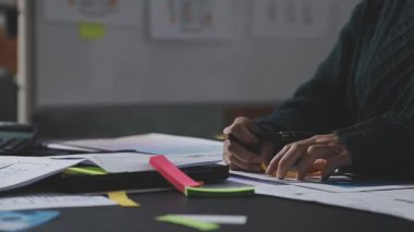 Hesap makinesi kullanan ve masa üzerinde grafik ve belgelerle muhasebe yapan işadamlarının ellerini kapat.