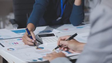 Hesap makinesi kullanan ve masa üzerinde grafik ve belgelerle muhasebe yapan işadamlarının ellerini kapat.