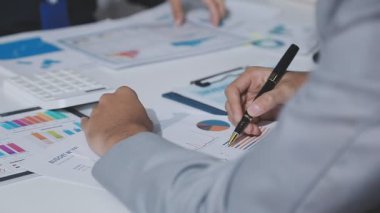 Hesap makinesi kullanan ve masa üzerinde grafik ve belgelerle muhasebe yapan işadamlarının ellerini kapat.