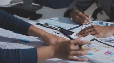 Hesap makinesi kullanan ve masa üzerinde grafik ve belgelerle muhasebe yapan işadamlarının ellerini kapat.