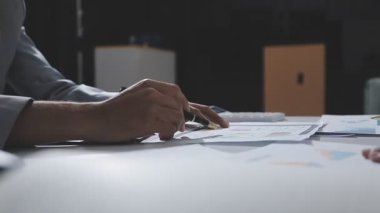 Hesap makinesi kullanan ve masa üzerinde grafik ve belgelerle muhasebe yapan işadamlarının ellerini kapat.