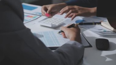 Hesap makinesi kullanan ve masa üzerinde grafik ve belgelerle muhasebe yapan işadamlarının ellerini kapat.