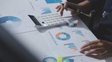 Hesap makinesi kullanan ve masa üzerinde grafik ve belgelerle muhasebe yapan işadamlarının ellerini kapat.