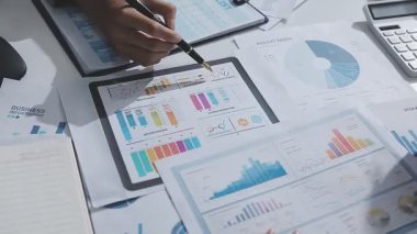 Hesap makinesi kullanan ve masa üzerinde grafik ve belgelerle muhasebe yapan işadamlarının ellerini kapat.